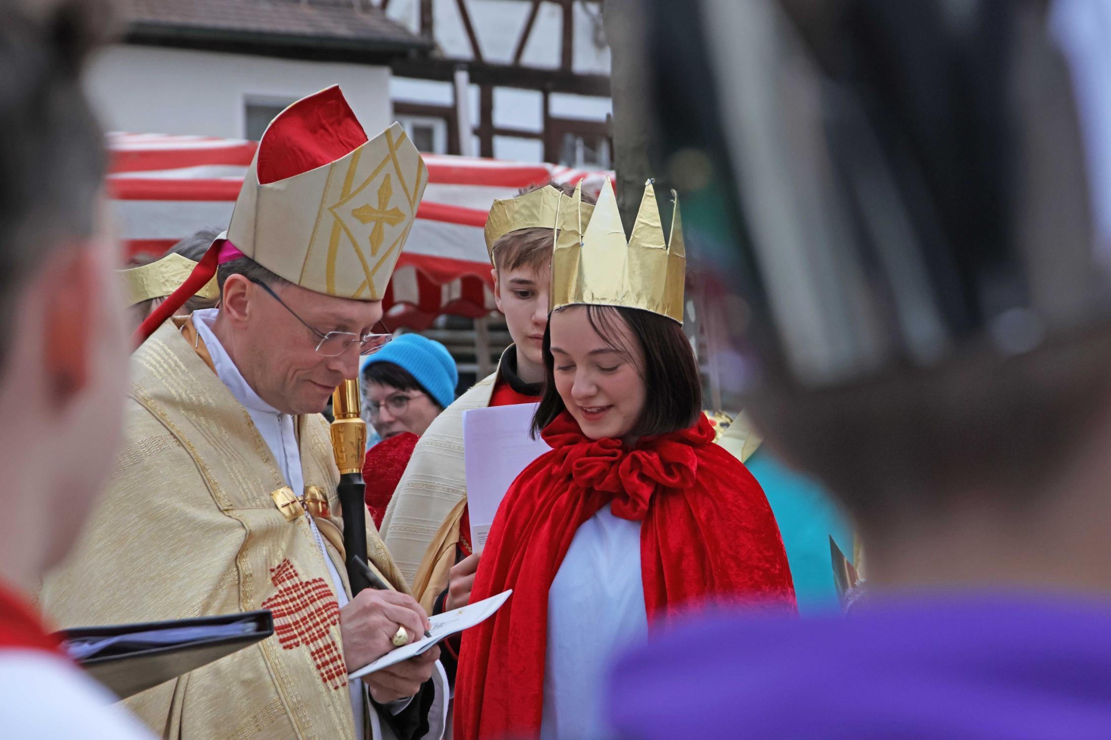 Weihbischof Herwig Gössl gibt einer Sternsingerin ein Autogramm.
